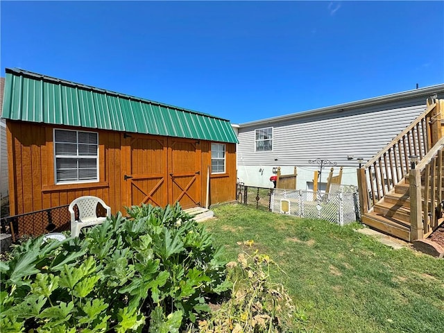 exterior space featuring a yard, metal roof, fence, and an outdoor structure