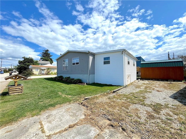 rear view of property featuring a lawn and an outbuilding