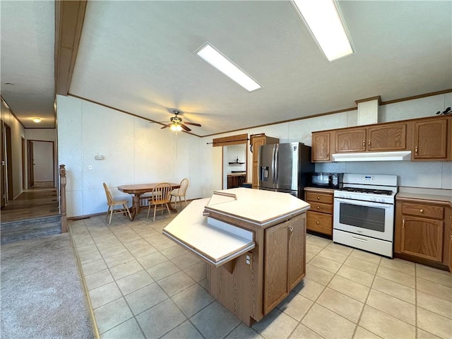 kitchen with under cabinet range hood, a center island, stainless steel refrigerator with ice dispenser, white gas range oven, and brown cabinets