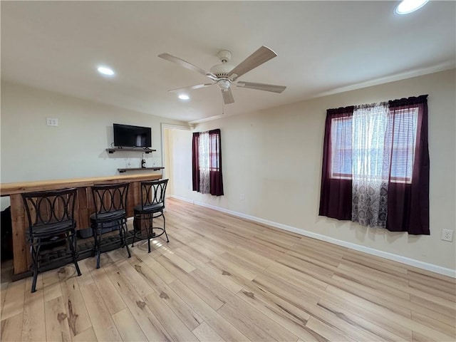 bar featuring baseboards, indoor bar, a ceiling fan, wood finished floors, and recessed lighting