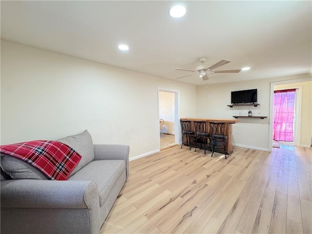 living room featuring recessed lighting, a ceiling fan, baseboards, light wood-style floors, and a dry bar