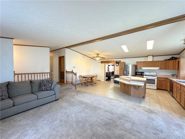 living room featuring crown molding, light tile patterned floors, light colored carpet, ceiling fan, and a textured ceiling