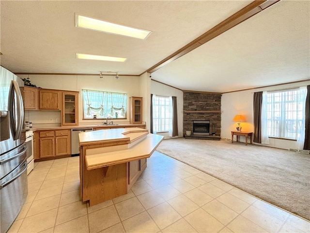 kitchen with stainless steel appliances, light colored carpet, lofted ceiling with beams, a sink, and plenty of natural light