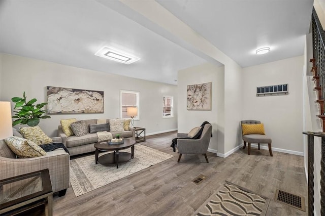 living room with baseboards, visible vents, and wood finished floors