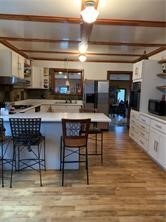 kitchen featuring beamed ceiling, a kitchen bar, white cabinets, and hardwood / wood-style flooring