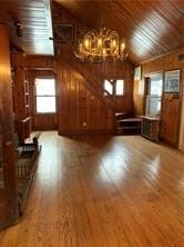 unfurnished living room with wood walls, wooden ceiling, vaulted ceiling, and hardwood / wood-style floors