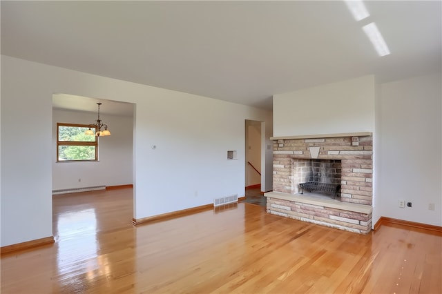 unfurnished living room with a fireplace, baseboard heating, a chandelier, and wood-type flooring