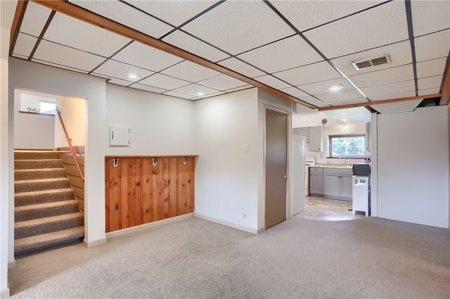 basement with sink, light carpet, and a paneled ceiling