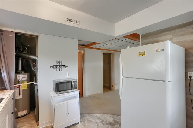 kitchen featuring water heater, white fridge, light tile patterned floors, and white cabinetry