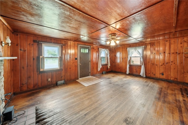 entrance foyer featuring hardwood / wood-style flooring, ceiling fan, wood walls, and a wealth of natural light