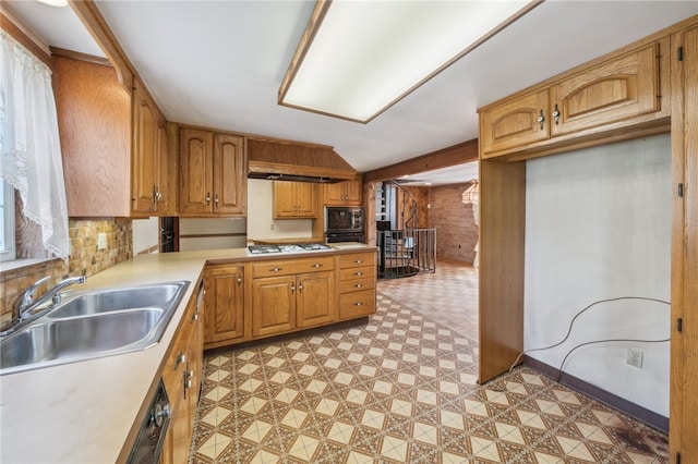 kitchen featuring black microwave, sink, wooden walls, and stainless steel gas cooktop