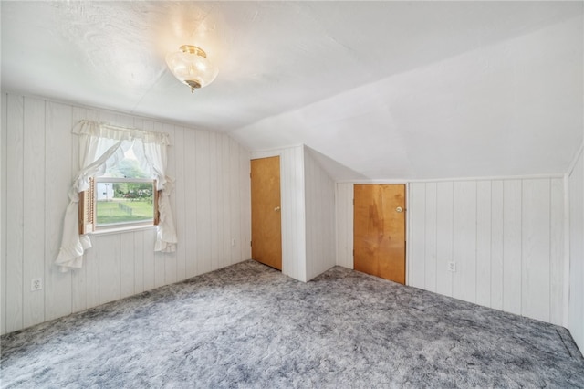 bonus room featuring carpet flooring, wooden walls, and vaulted ceiling