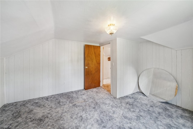 bonus room featuring wooden walls, carpet floors, and vaulted ceiling