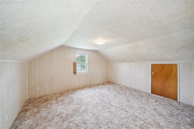 bonus room with carpet flooring, lofted ceiling, and a textured ceiling