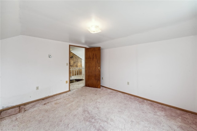 spare room featuring carpet flooring and vaulted ceiling