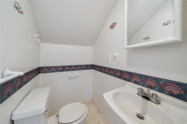 bathroom with toilet, vaulted ceiling, and sink