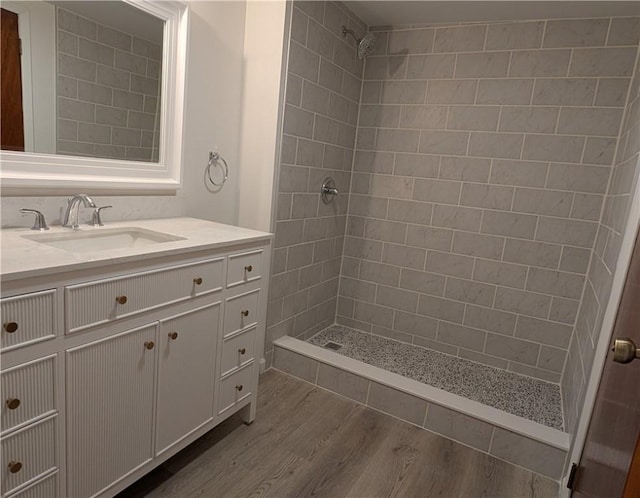 bathroom with a tile shower, hardwood / wood-style floors, and vanity