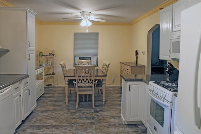 kitchen with dark countertops, white appliances, white cabinets, and crown molding