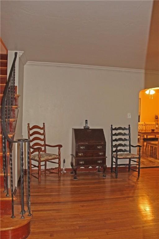 living area featuring ornamental molding, arched walkways, stairway, and wood finished floors