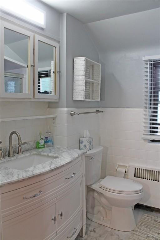 bathroom featuring radiator heating unit, tile walls, toilet, and vanity