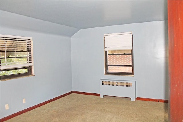 spare room featuring carpet, radiator, lofted ceiling, and baseboards