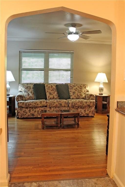 living area featuring plenty of natural light, ornamental molding, arched walkways, and wood finished floors