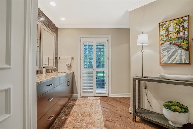 bathroom with crown molding, wood-type flooring, and vanity