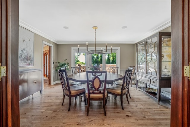 dining room with hardwood / wood-style floors, crown molding, and a notable chandelier