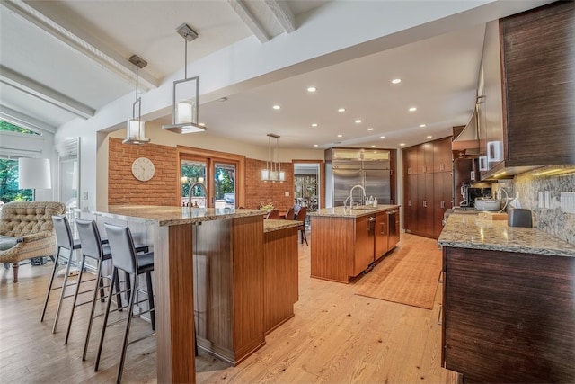 kitchen with light wood-type flooring, lofted ceiling with beams, stainless steel built in fridge, pendant lighting, and a large island