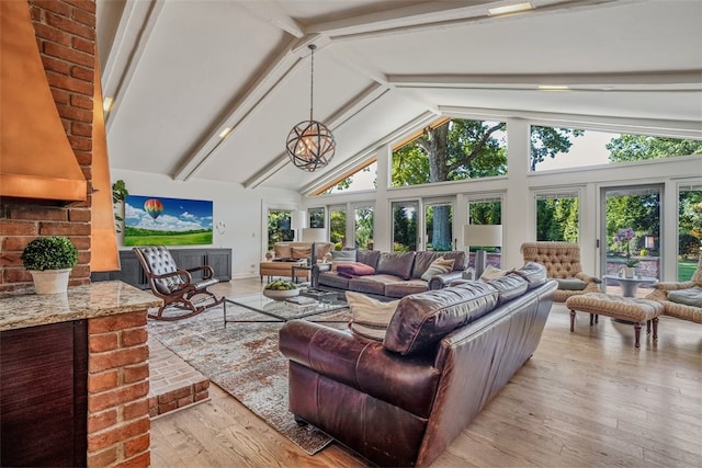 living room with high vaulted ceiling, beamed ceiling, light hardwood / wood-style floors, and brick wall