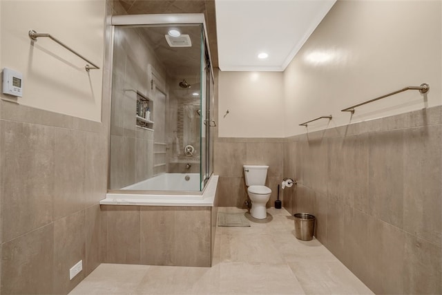 bathroom featuring toilet, tile patterned flooring, ornamental molding, tile walls, and tiled shower / bath