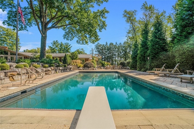 view of swimming pool featuring a diving board and a patio