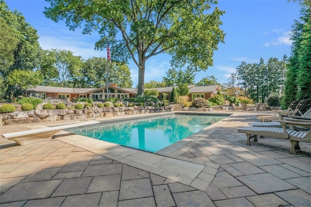 view of swimming pool featuring a diving board and a patio area