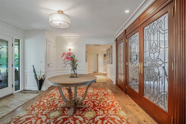 foyer with ornamental molding, light wood-type flooring, and french doors