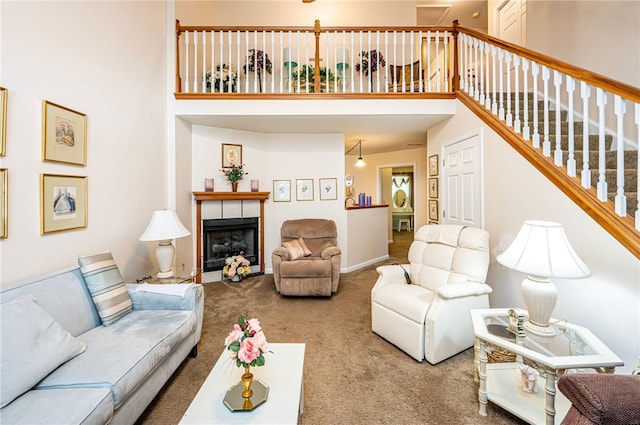 living room with carpet, a towering ceiling, and a fireplace