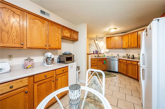 kitchen with sink, stainless steel dishwasher, light tile patterned floors, and white fridge