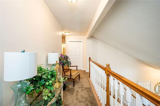 hall with vaulted ceiling with beams and light colored carpet