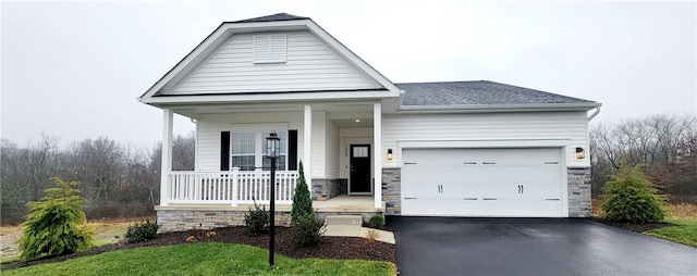 view of front of home featuring a porch, a garage, and a front lawn