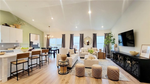 living room with a chandelier, light wood-type flooring, and high vaulted ceiling