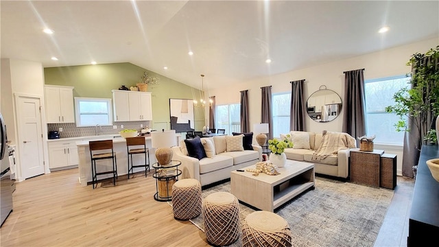 living room with light wood-type flooring, an inviting chandelier, and a wealth of natural light