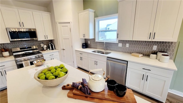 kitchen with tasteful backsplash, white cabinetry, sink, and stainless steel appliances