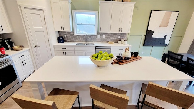 kitchen featuring backsplash, sink, appliances with stainless steel finishes, a kitchen island, and white cabinetry