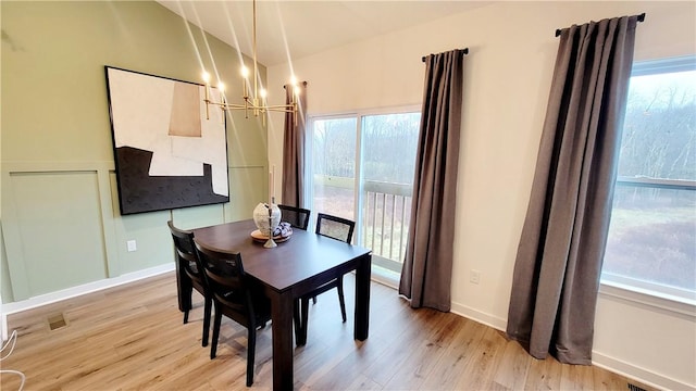 dining space featuring a notable chandelier, a healthy amount of sunlight, and light wood-type flooring