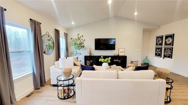 living room with light wood-type flooring and vaulted ceiling