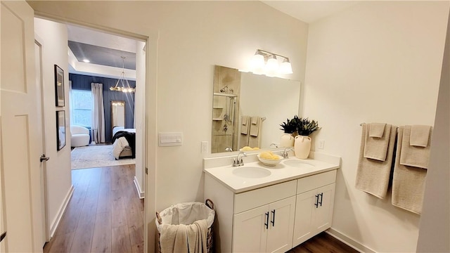 bathroom featuring hardwood / wood-style floors, vanity, a shower with shower door, and a notable chandelier