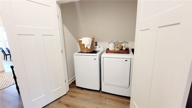 clothes washing area featuring washing machine and dryer and light hardwood / wood-style floors