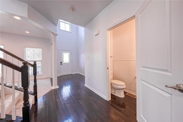 entrance foyer with tile walls, hardwood / wood-style flooring, and ornate columns