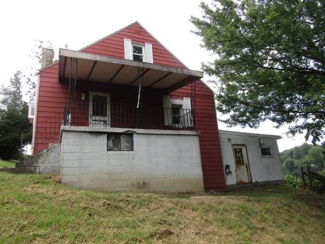 back of property featuring a balcony and a yard