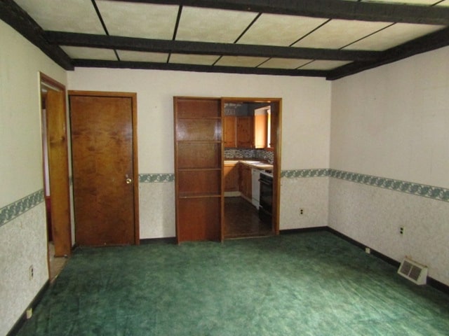 unfurnished bedroom featuring beamed ceiling and dark carpet