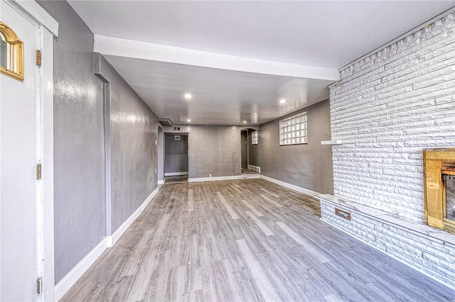 basement with hardwood / wood-style floors and brick wall